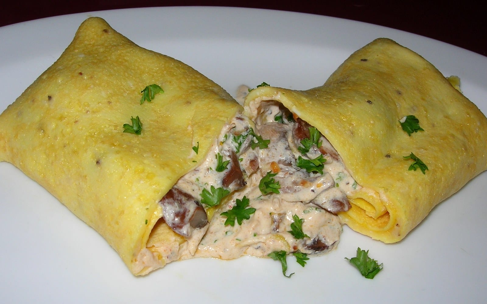 Folded golden omelette opened to reveal a creamy mushroom filling