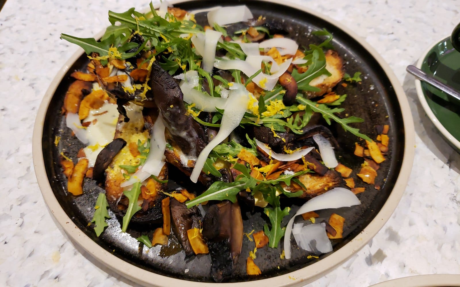 Creamy mushroom toast topped with clearly visible cooked mushrooms and rocket